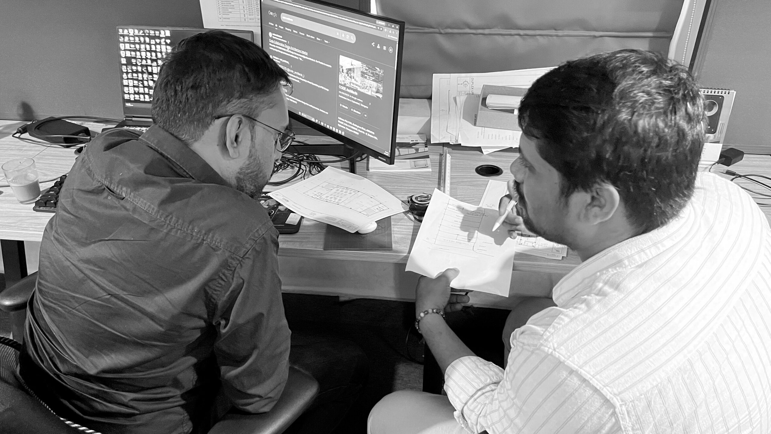 Two colleagues discussing a CAD drawing on screen